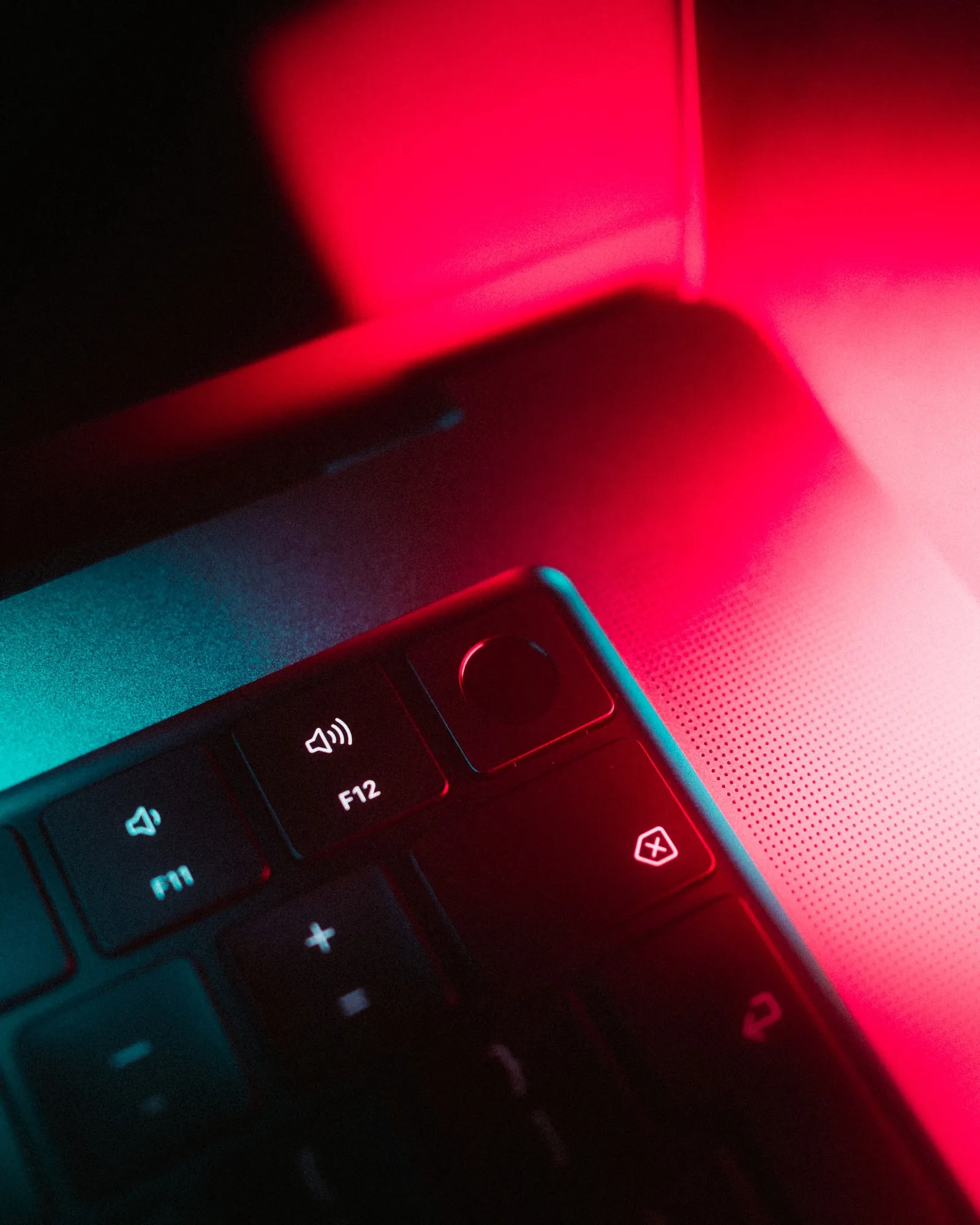 top-right corner of MacBook Pro 2021 keyboard, in moody, red and teal lighting.