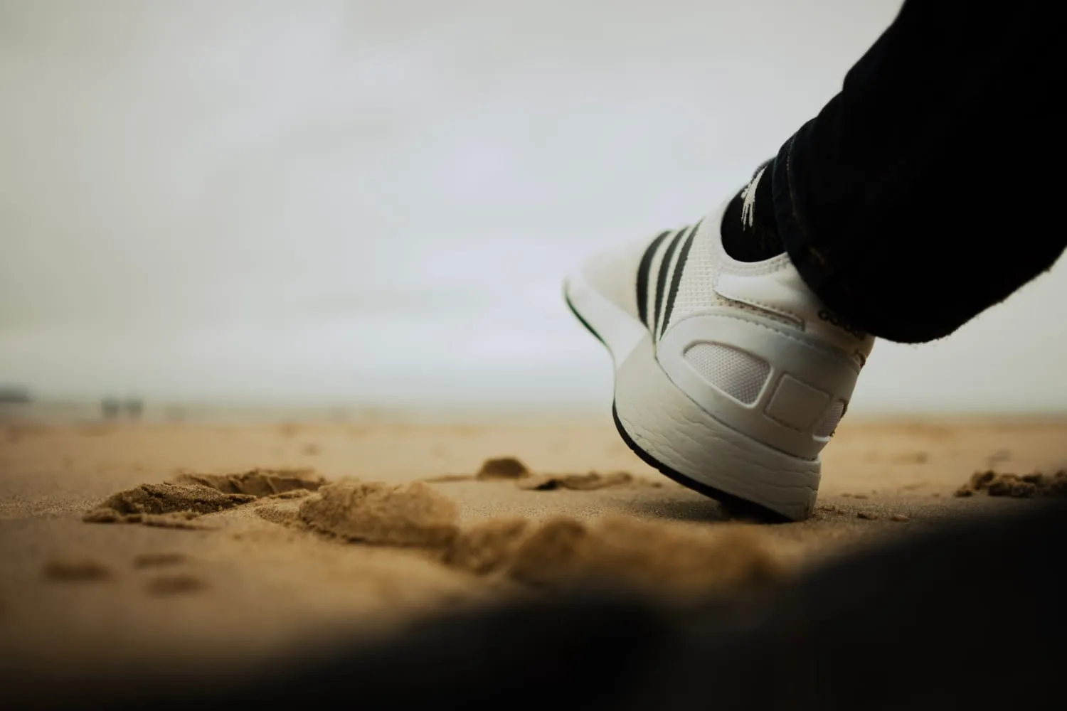 person sitting on a beach, with their feet in the sand