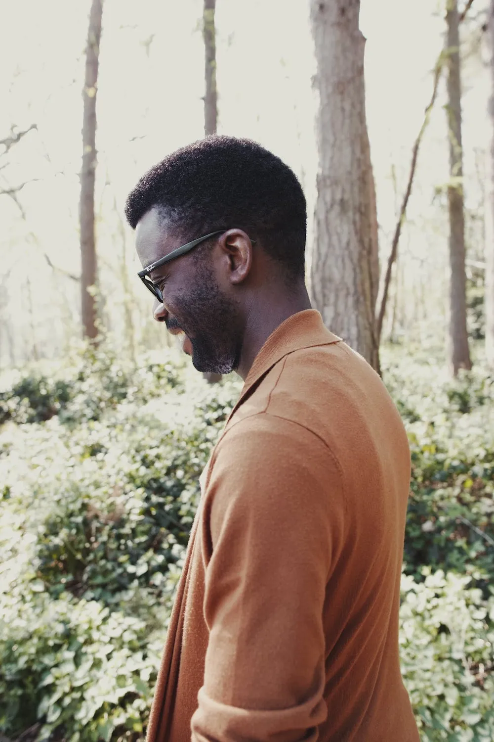 man in park, smiling, looking down on the ground